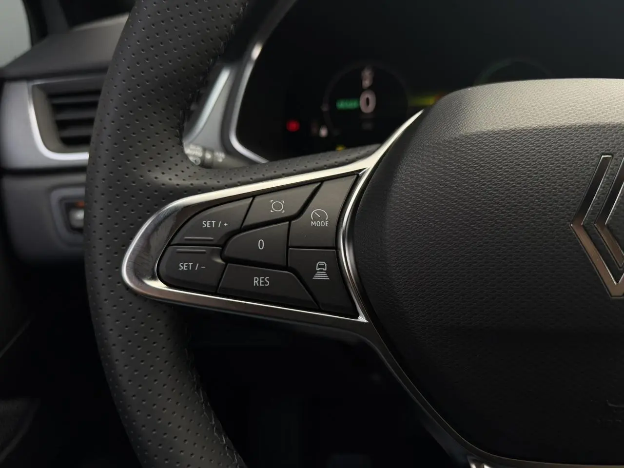 Gros plan sur le volant en textile perforé du Renault Captur gris Rafale, avec commandes intégrées côté gauche.