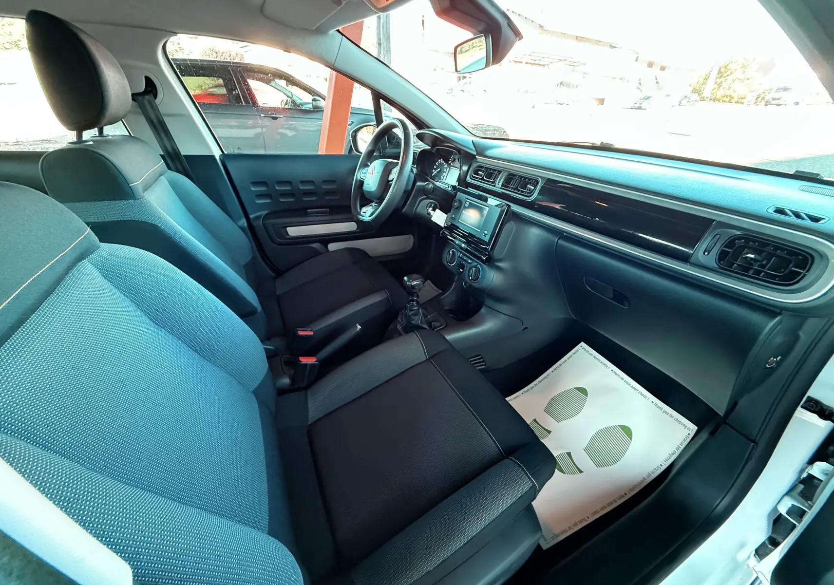 Intérieur de la Citroën C3 blanc vu côté passager, montrant sièges noirs et tableau de bord avec écran tactile central.
