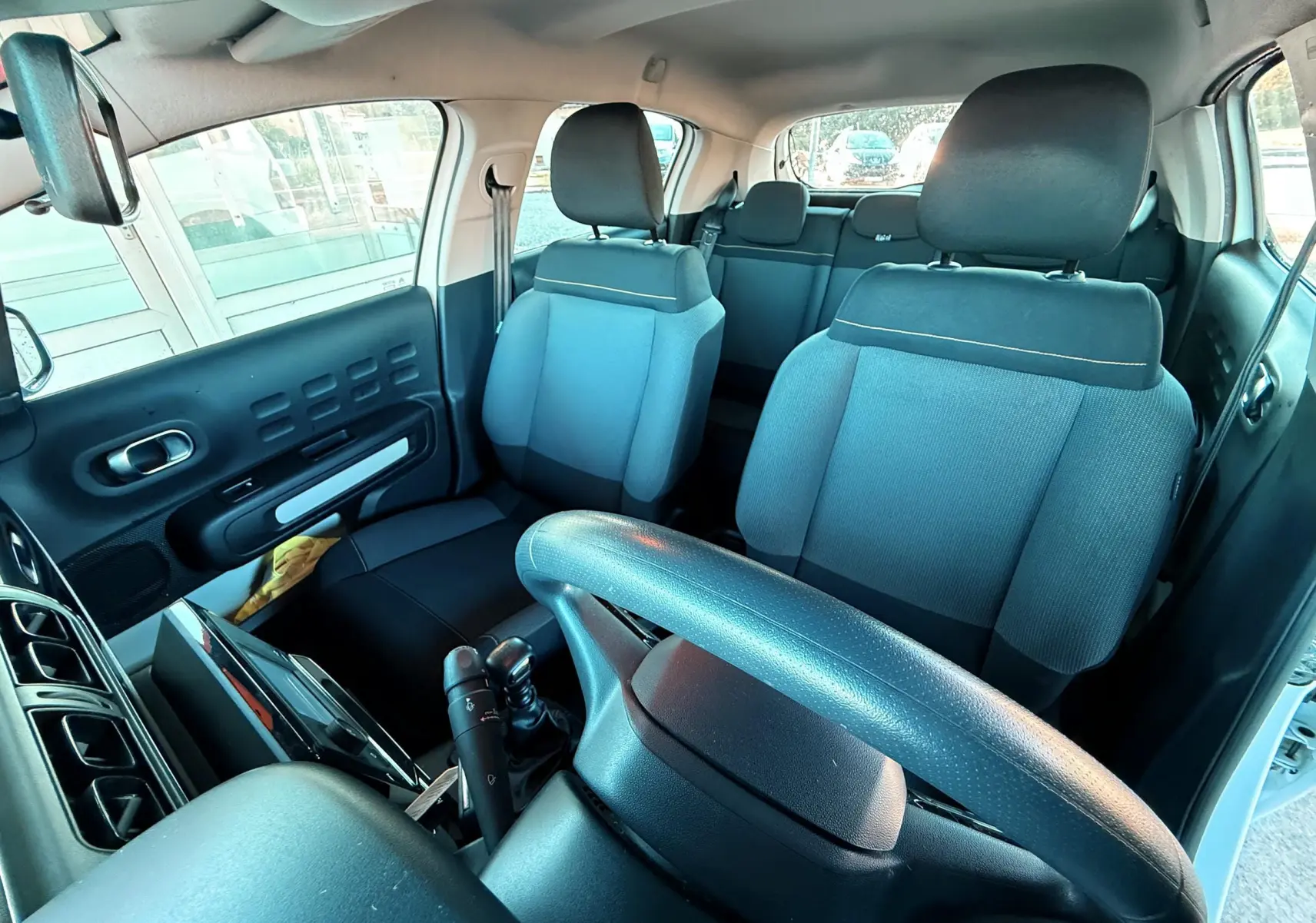 Vue intérieure avant de la Citroën C3 blanche de 2021, montrant les sièges avant et le volant côté gauche.