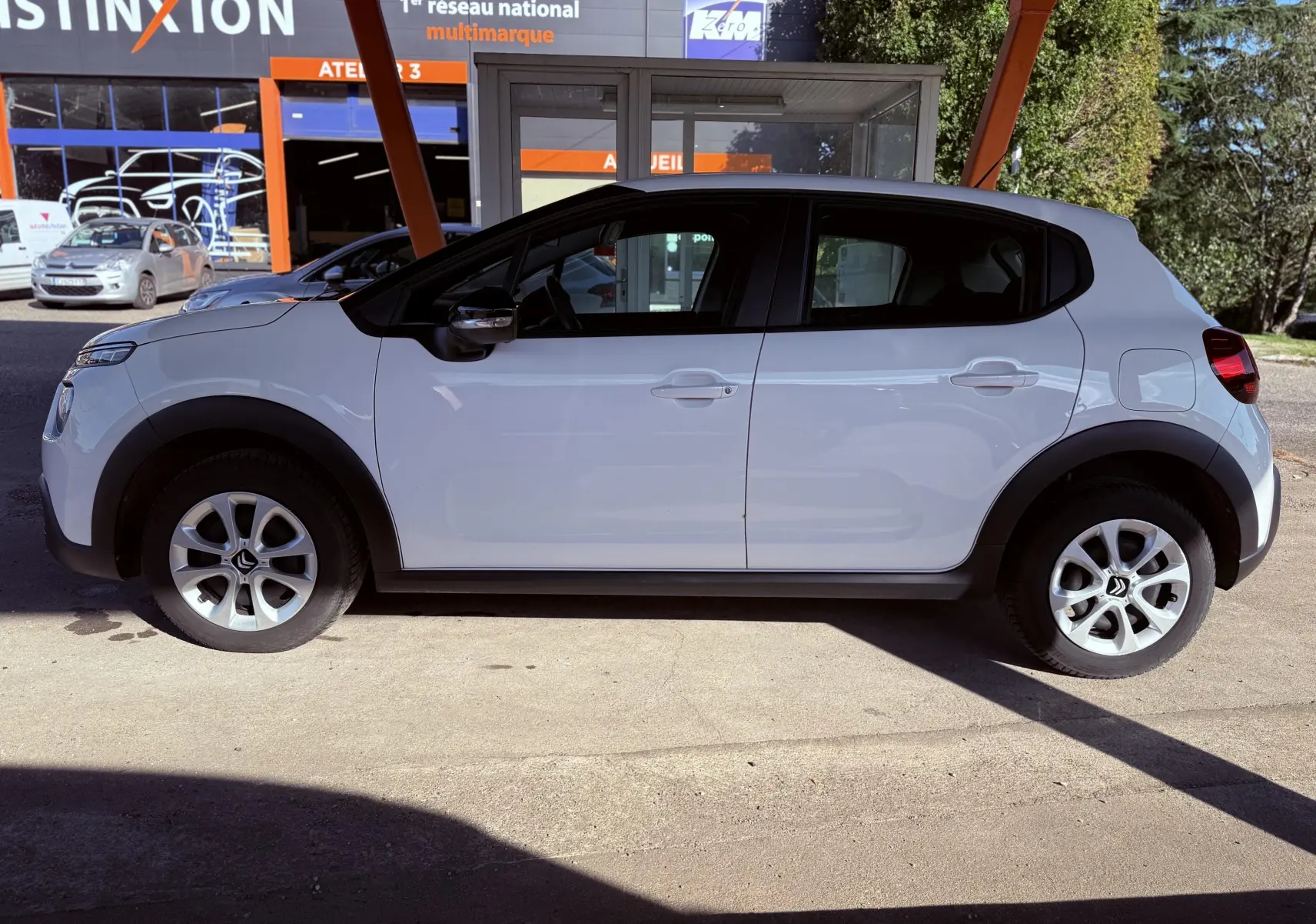 Profil côté gauche d'une Citroën C3 blanche de 2021, avec jantes alliage et protections noires sur les passages de roues.