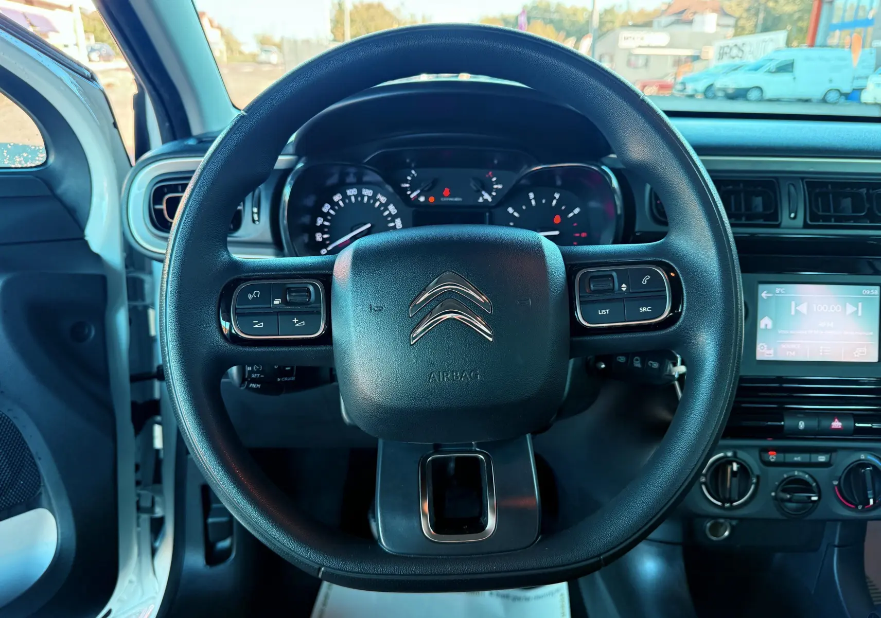 Vue centrée sur le volant noir du Citroën C3 blanc, avec tableau de bord et écran tactile visibles à droite.