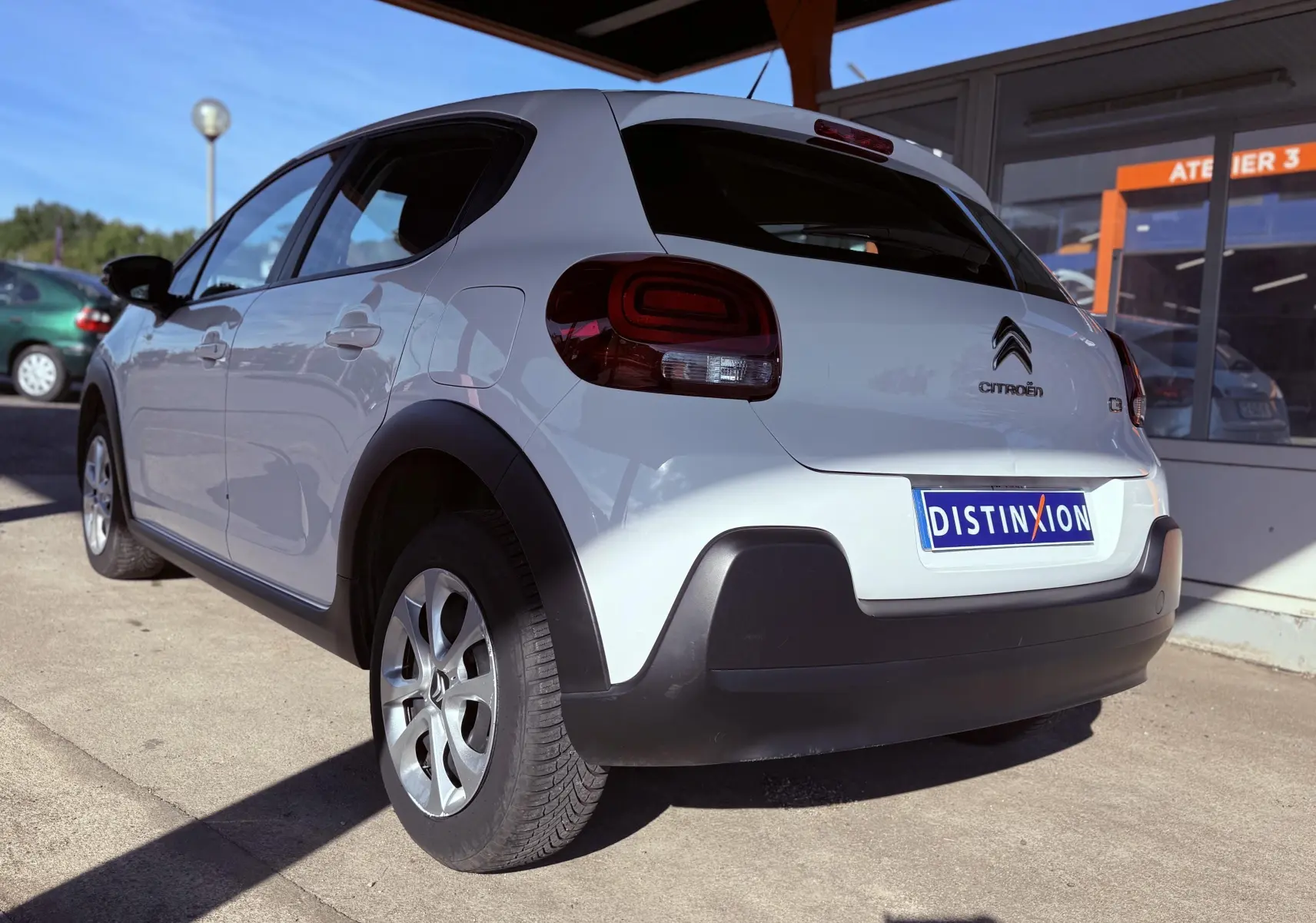 Vue 3/4 arrière droite d'une Citroën C3 blanche avec feux arrière arrondis et protections noires sur les passages de roue.