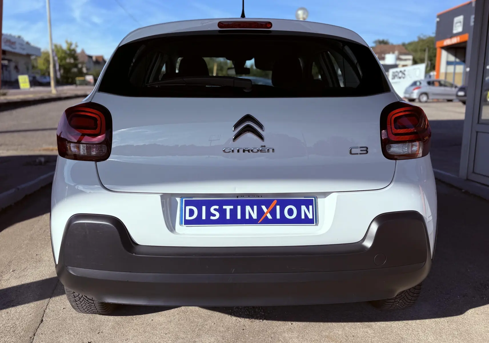 Vue arrière d'une Citroën C3 blanche de 2021 avec logo et plaque Distinxion, pare-chocs noir mat visible.
