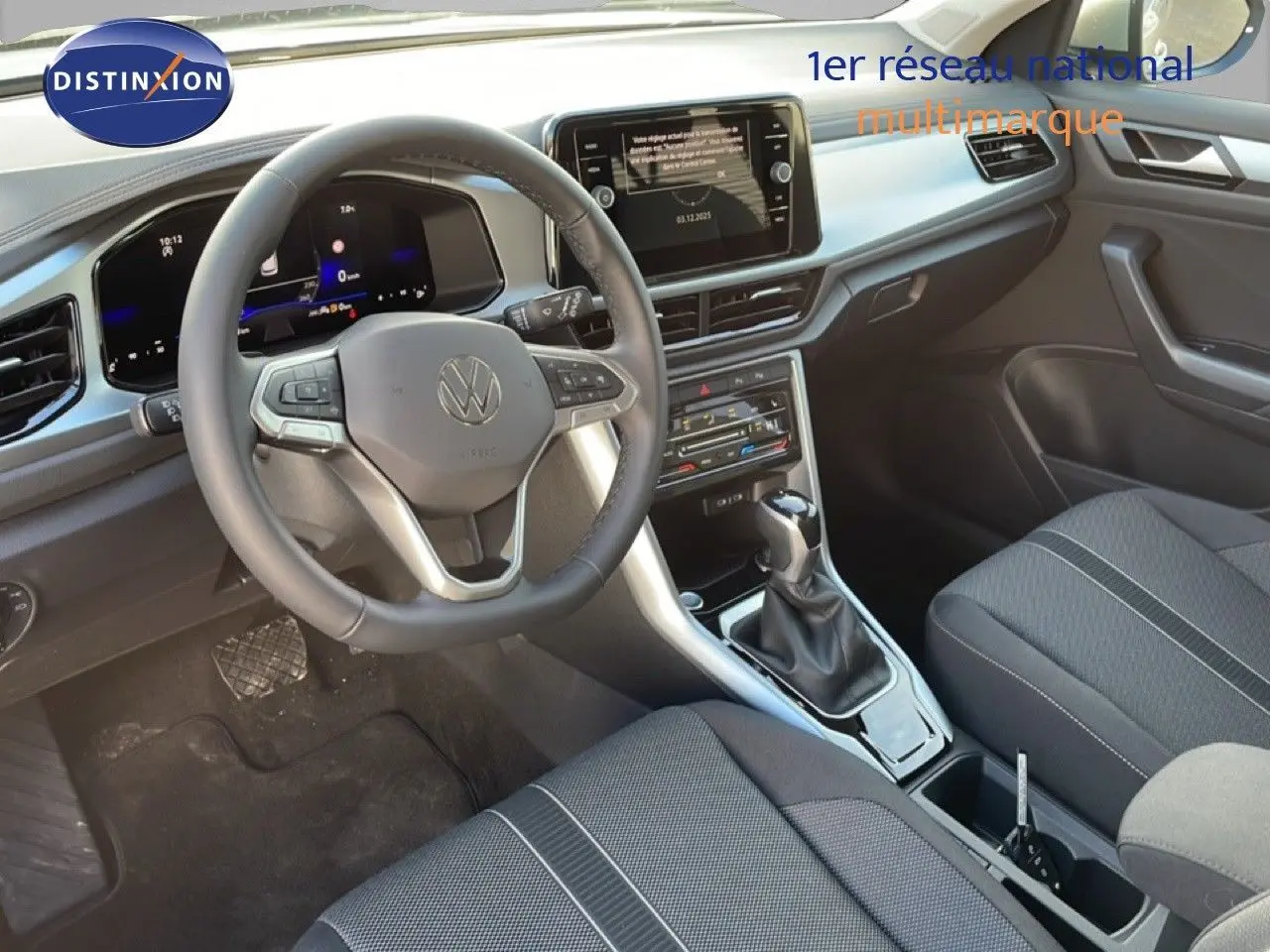 Vue intérieure du Volkswagen T-Roc 2025 montrant le volant, la console centrale avec boîte auto et les sièges en tissu noir.