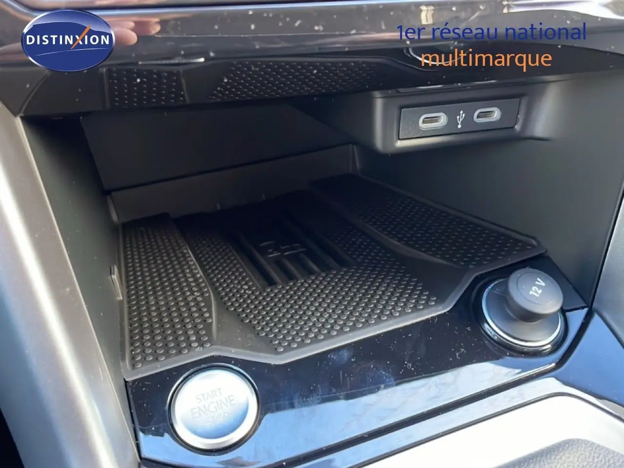 Gros plan sur la console centrale du Volkswagen T-Roc 2025, montrant le bouton start/stop, prise 12V et ports USB.