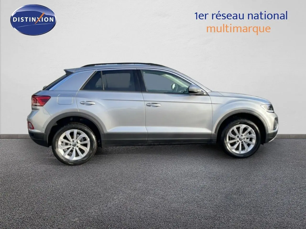 Vue de profil côté gauche d'un Volkswagen T-Roc gris pyrite métal 2025 sur fond clair, avec jantes alliage visibles.