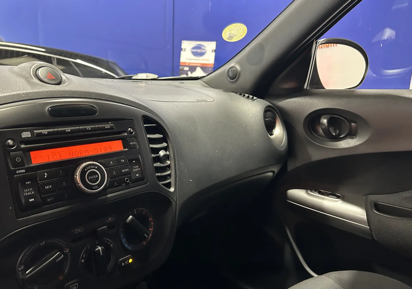 Vue intérieure côté passager du tableau de bord noir du Nissan Juke dci 110 Acenta avec radio et commandes de climatisation.