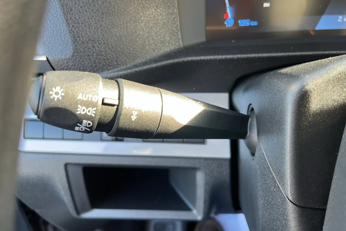 Gros plan sur la commande des feux au volant du Peugeot Traveller gris acier 2025, avec affichage numérique partiel.