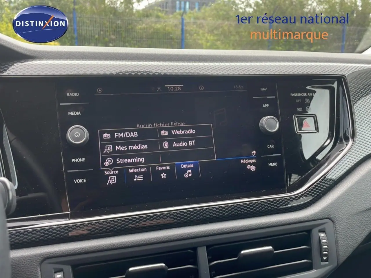 Vue rapprochée de l'écran multimédia tactile du tableau de bord de la Volkswagen Polo blanche, affichant les options audio.