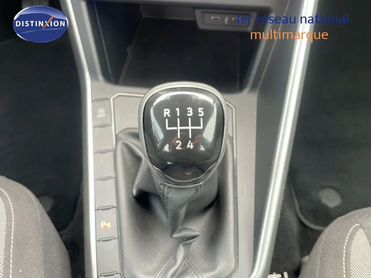 Le levier de vitesses manuel de la Volkswagen Polo 2022 en gros plan, entouré de sièges en tissu noir.