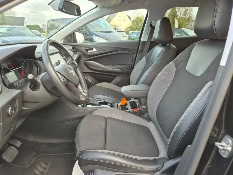 Vue intérieure côté conducteur de l'Opel Grandland X 2020 avec sièges noirs et gris et volant multifonction cuir.