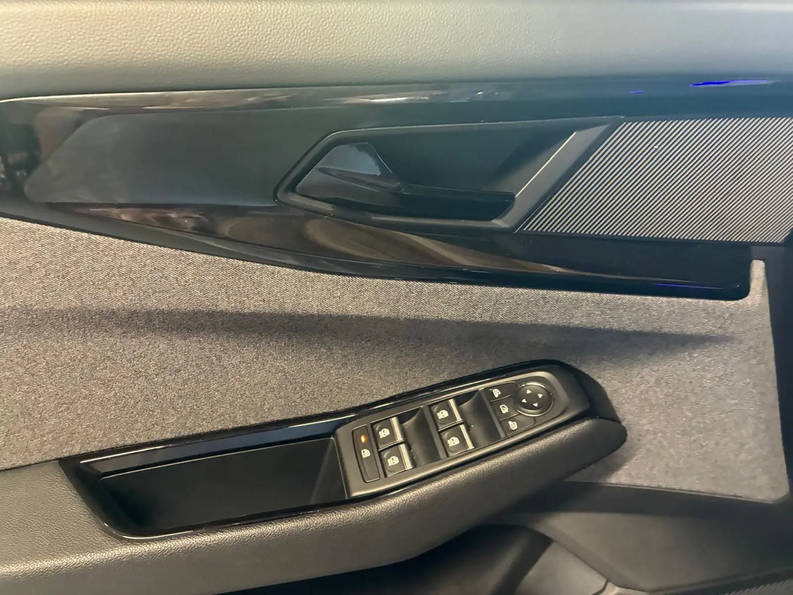Gros plan sur la porte intérieure côté conducteur du Renault Austral 2024, tissu gris et commandes de vitres noires.