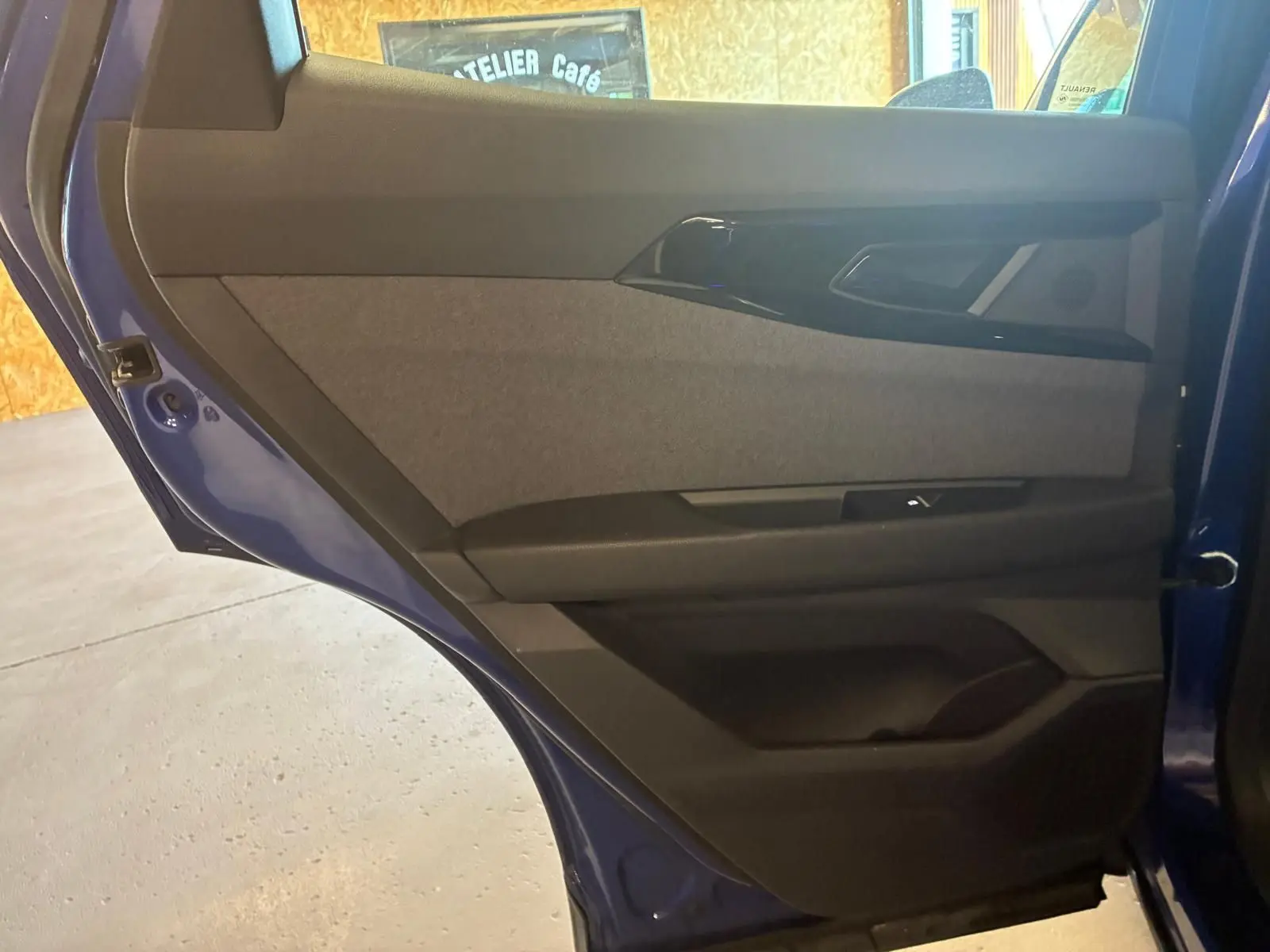 Vue rapprochée de la porte arrière droite bleu du Renault Austral 2024, montrant le revêtement tissu gris et les commandes.