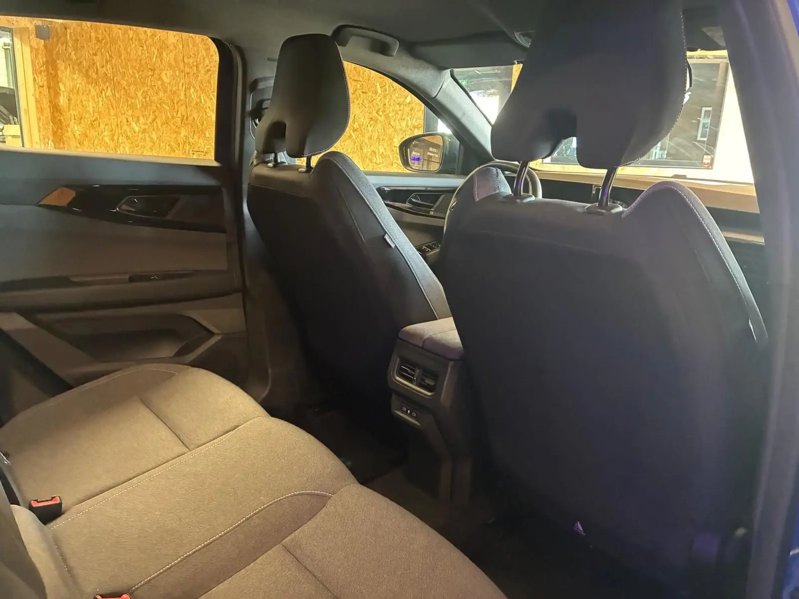 Vue intérieure arrière côté gauche du Renault Austral 2024, sièges tissu gris-noir et console centrale avec aérateurs.
