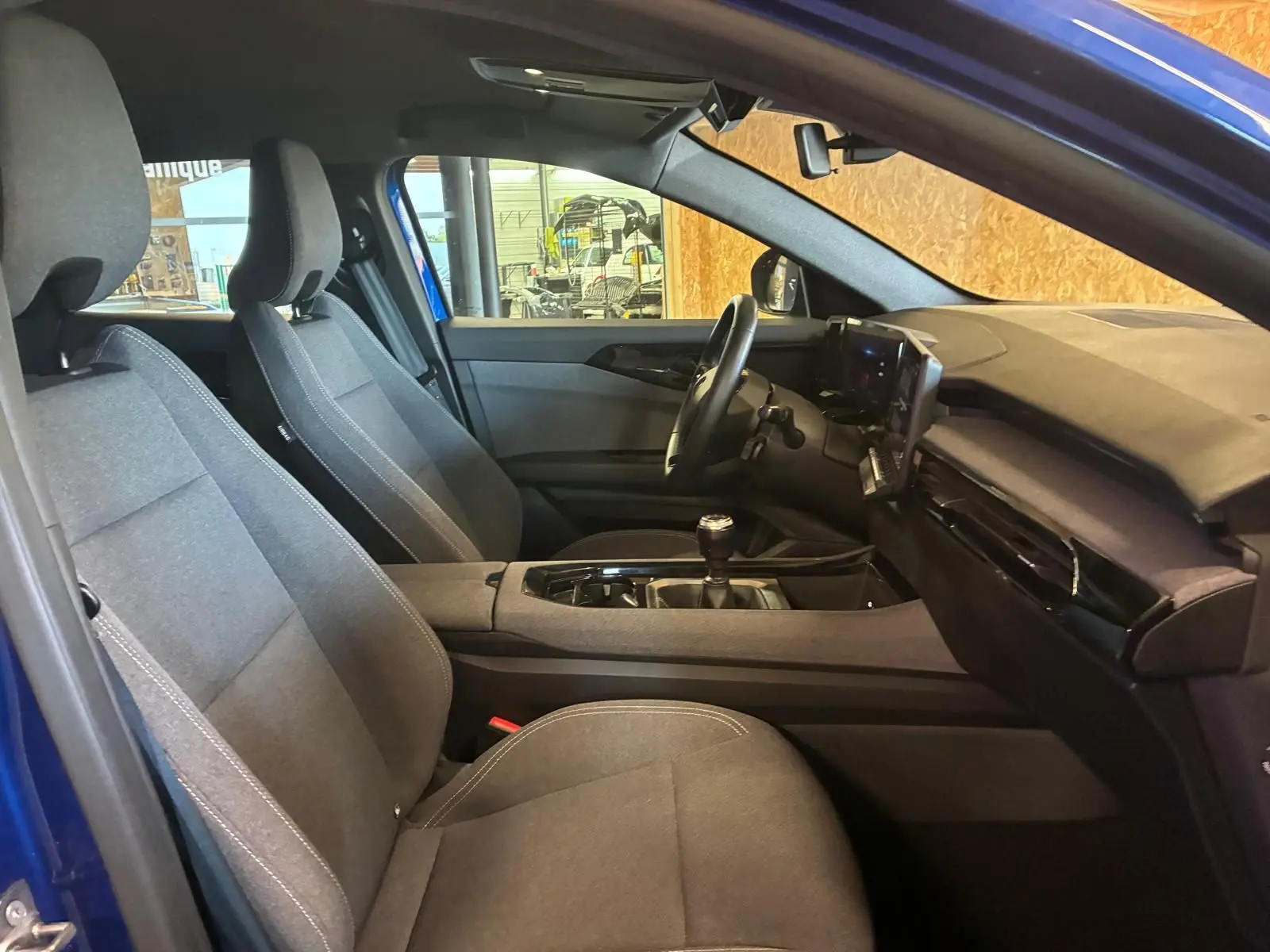 Vue intérieure côté gauche du Renault Austral bleu 2024, montrant les sièges tissu gris et la console avec boîte manuelle.