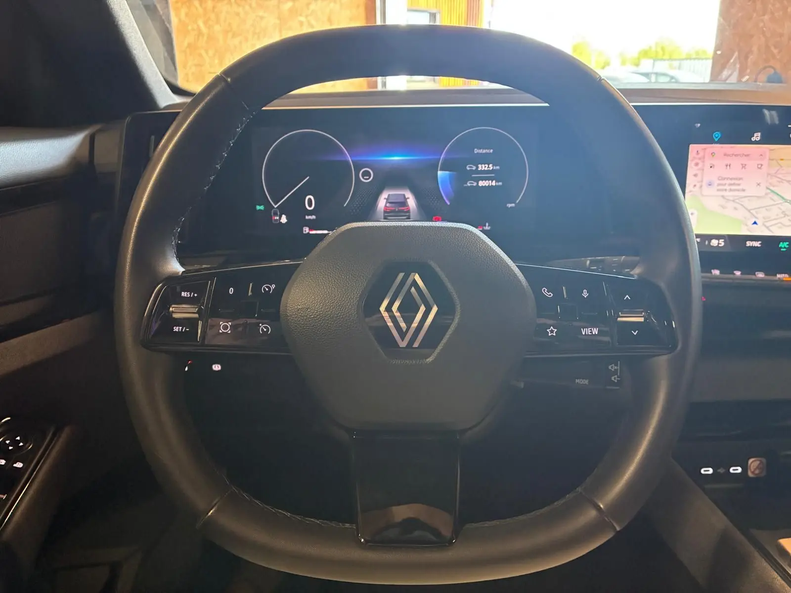 Vue intérieure centrée sur le volant noir de la Renault Austral 2024 avec tableau de bord numérique et écran tactile.