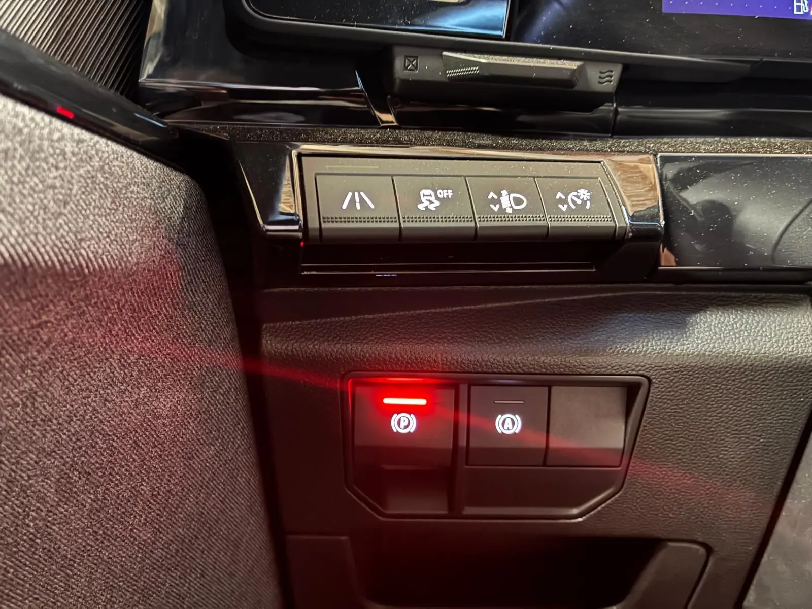 Gros plan sur les commandes du tableau de bord du Renault Austral bleu 2024, avec bouton de frein à main électronique allumé.