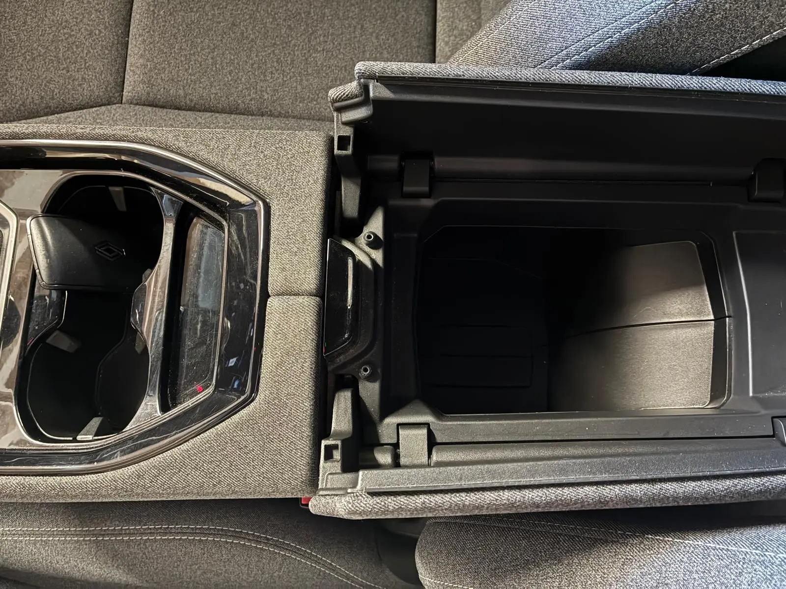 Vue en plongée sur la console centrale du Renault Austral 2024 bleu, montrant le rangement ouvert et les porte-gobelets.