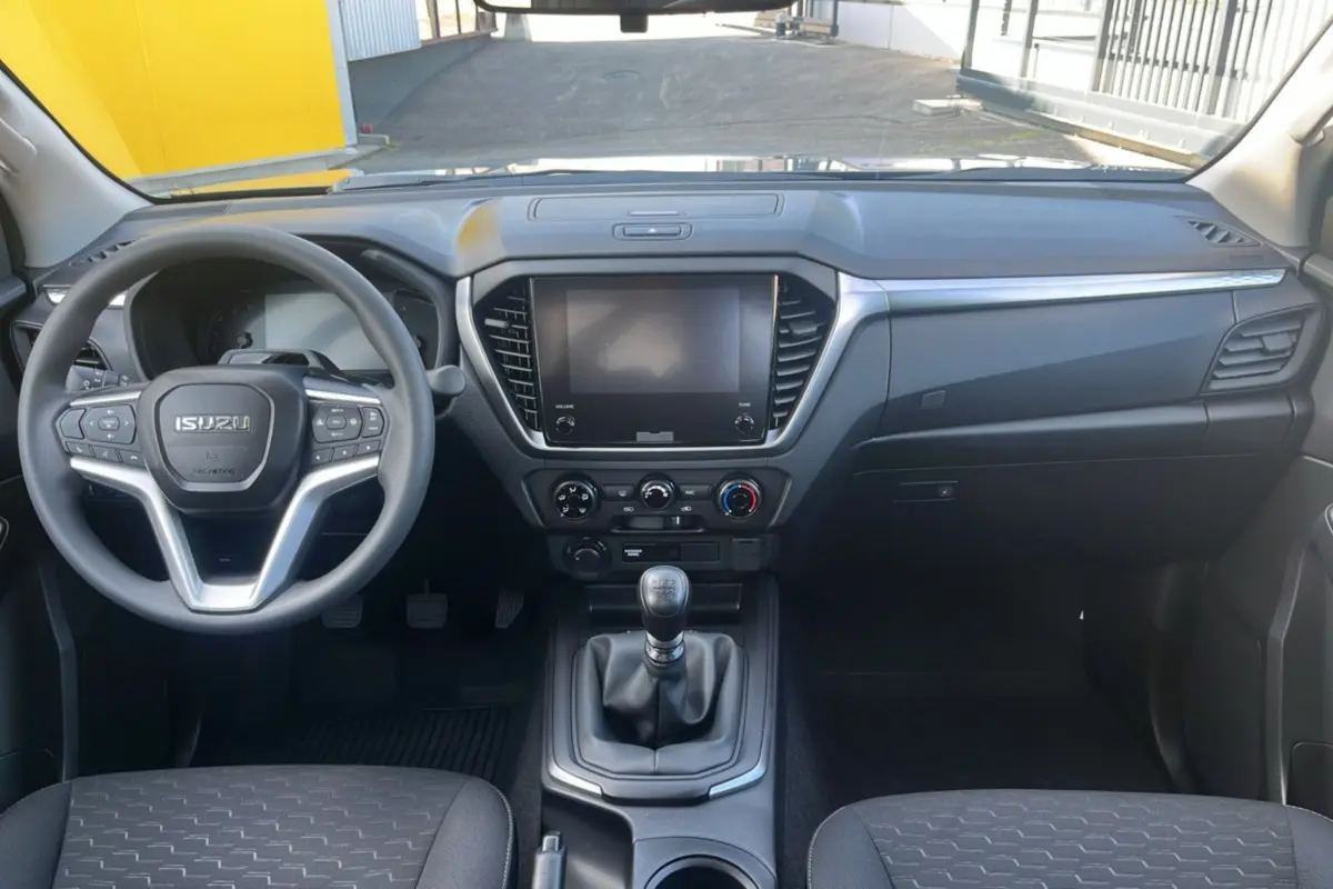 Vue intérieure avant de l'Isuzu D-MAX 2.2 TD 164 Space Evolution avec tableau de bord noir et volant multifonctions.