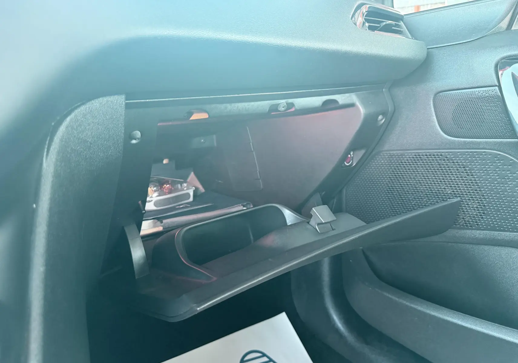 Gros plan sur la boîte à gants ouverte côté passager du Peugeot 208 blanc, version 1.4 hdi 70ch Active de 2013.