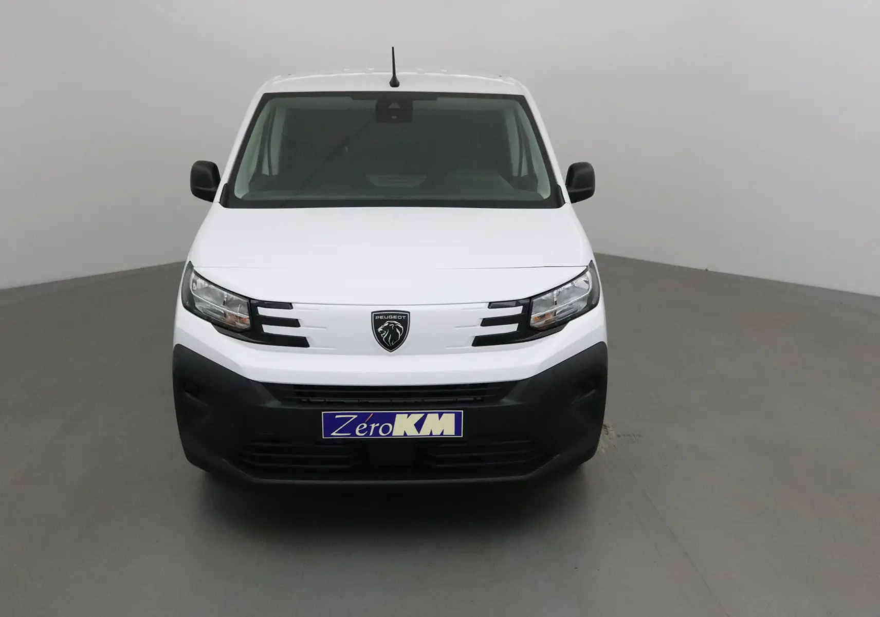 Vue frontale d'un utilitaire Peugeot Partner blanc avec calandre noire et logo lion central, sur fond neutre.