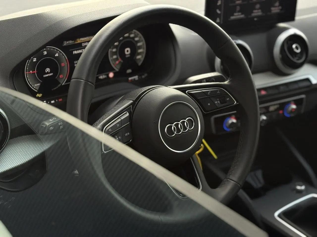 Vue rapprochée du volant multifonction en cuir noir et du tableau de bord numérique de l'Audi Q2 30 TDI S-Line.