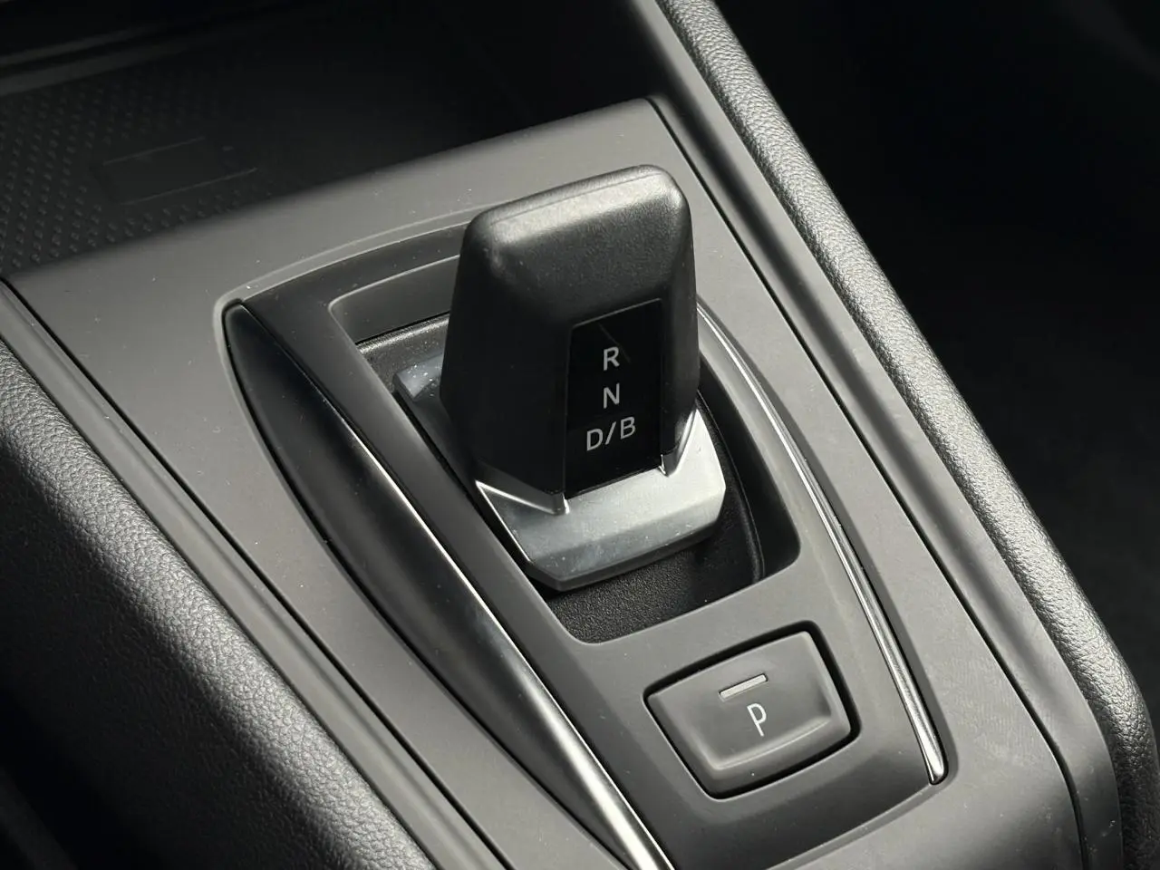 Gros plan sur la commande de boîte automatique noire du Renault Captur hybride, entourée de plastique gris et noir.