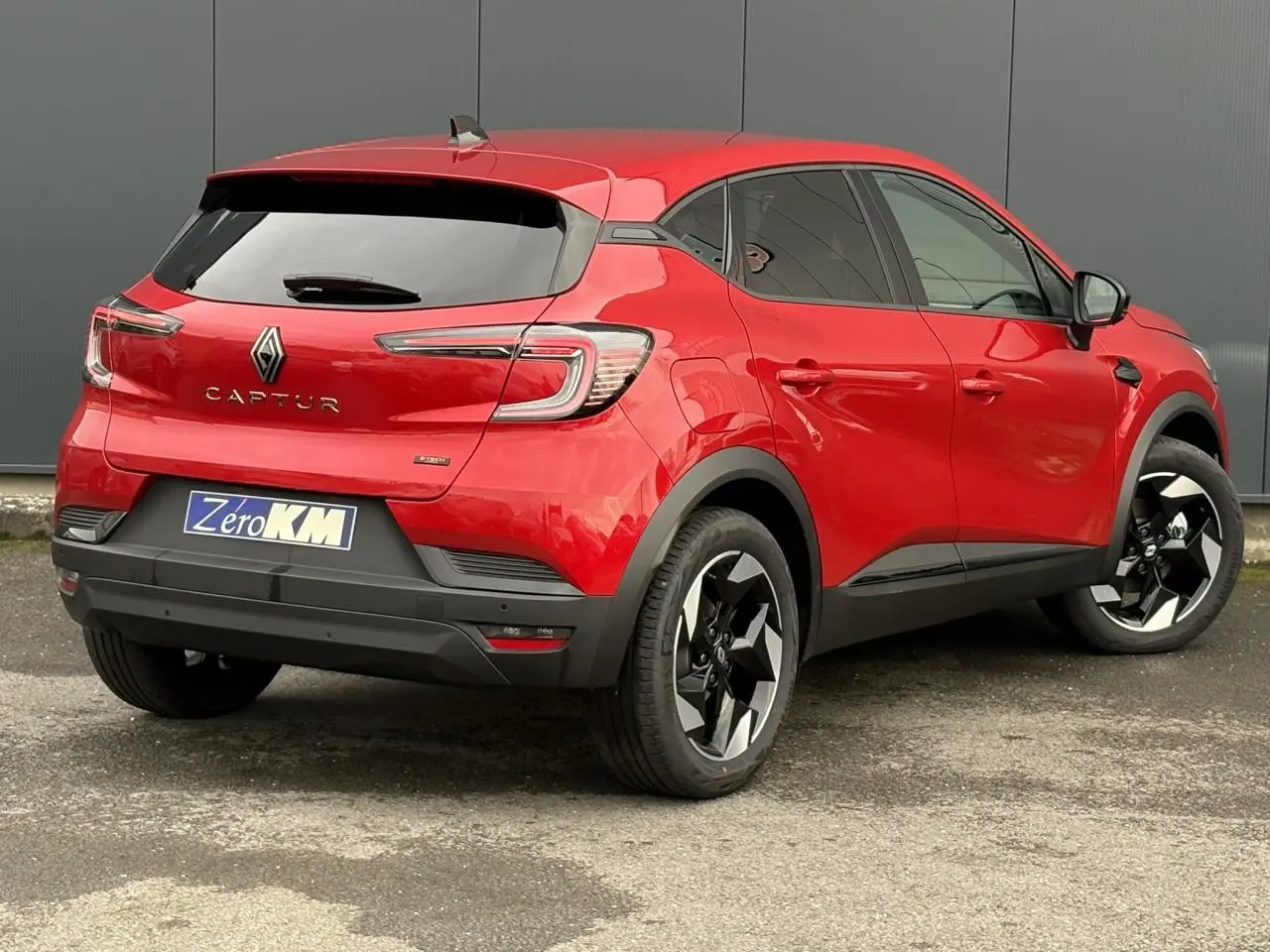 Vue 3/4 arrière droite du Renault Captur rouge flamme avec jantes aluminium 18 pouces et vitres surteintées.