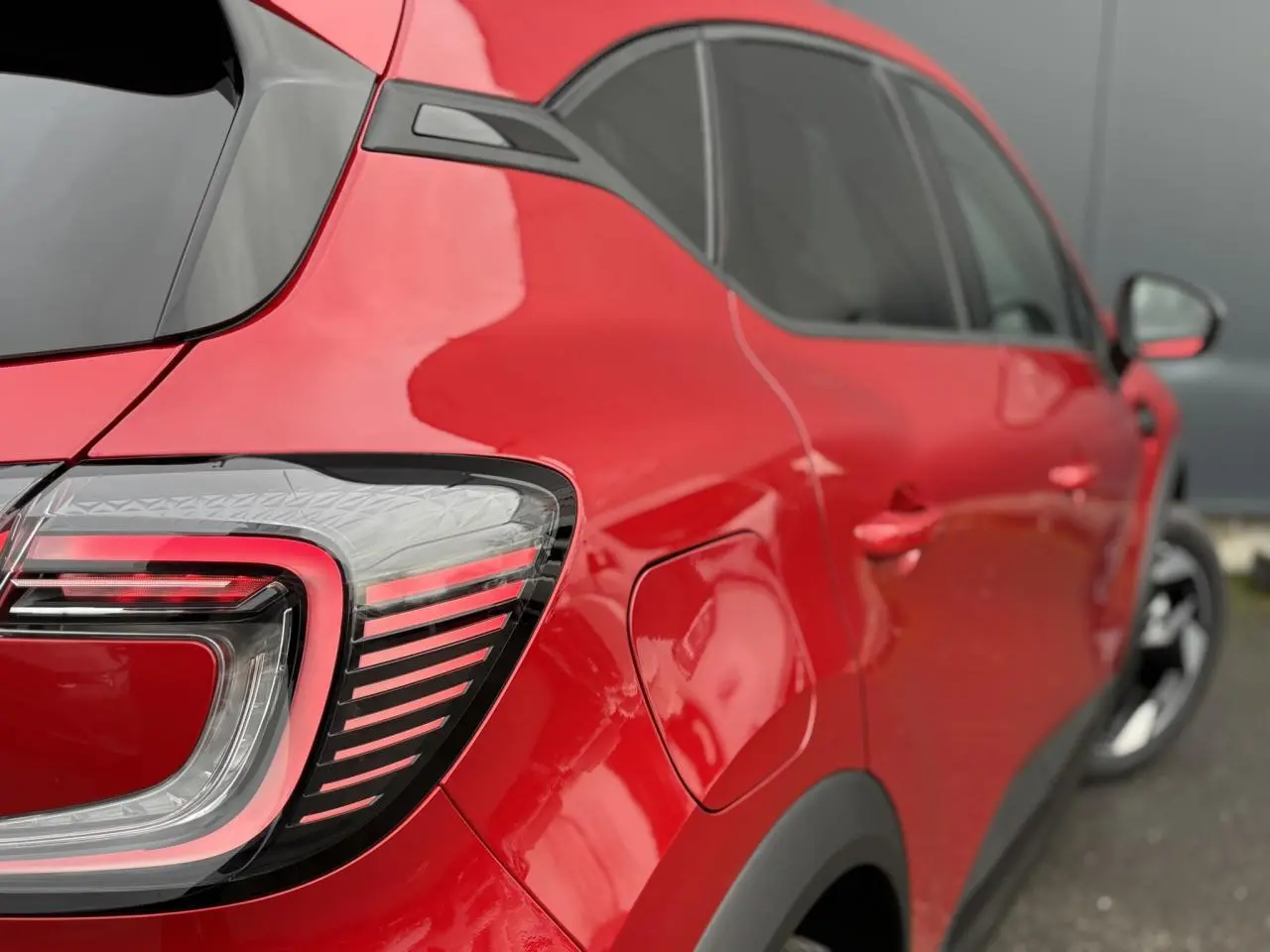 Vue arrière côté gauche du Renault Captur 2026 rouge Flamme avec feux LED et jantes aluminium noires.