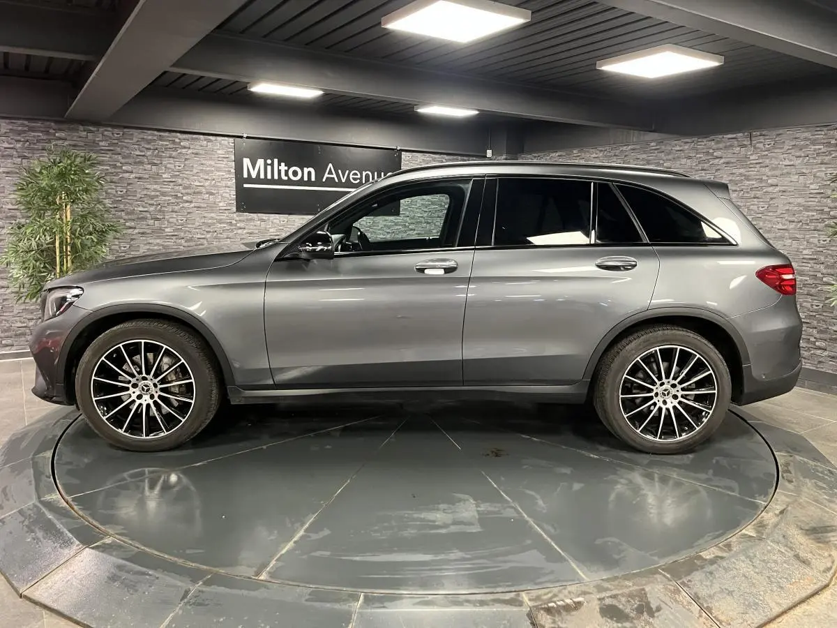 Profil droit d'un Mercedes GLC gris métallisé 2019 avec jantes alliage AMG 20 pouces multibranches dans un showroom.
