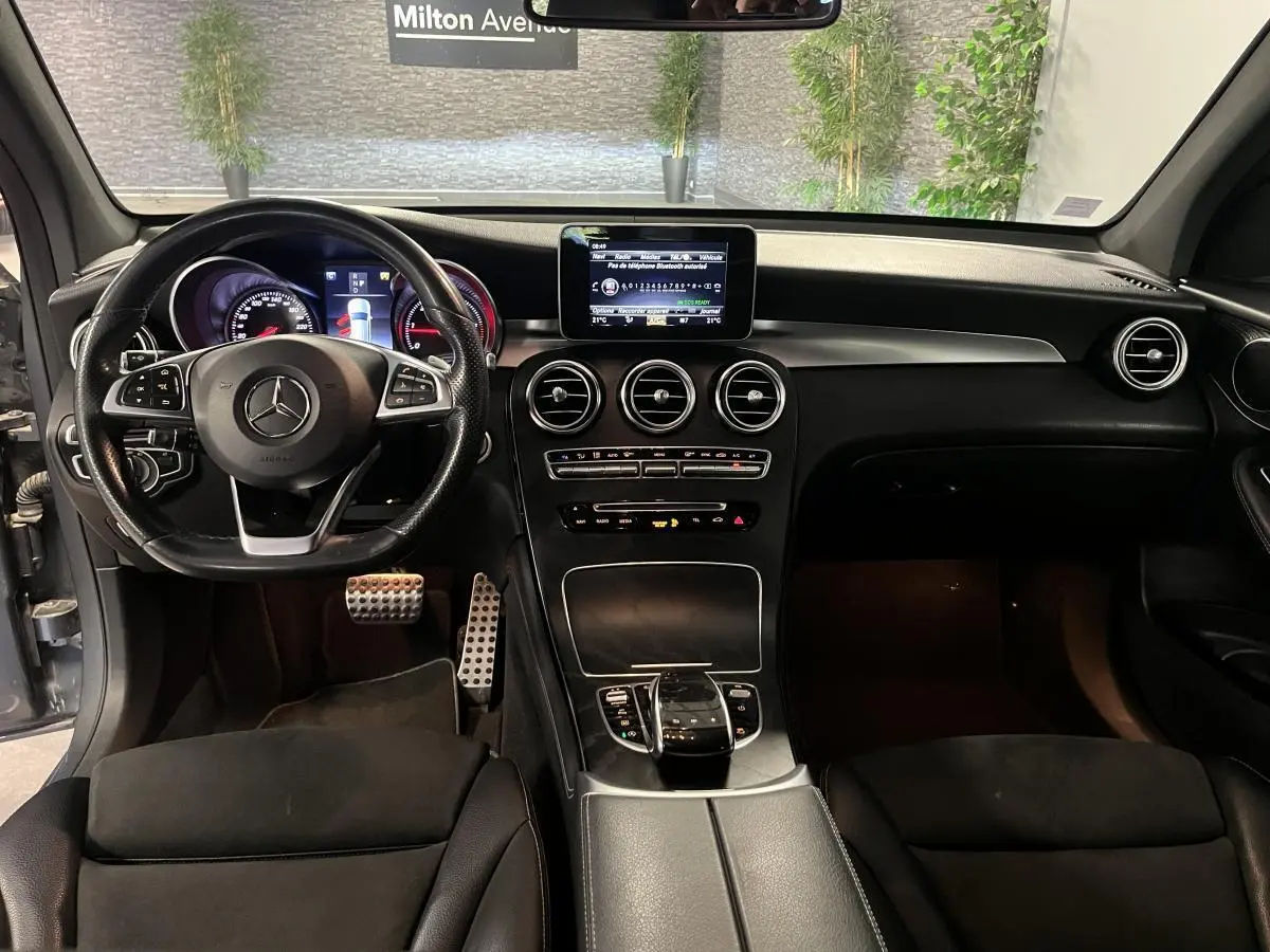 Vue intérieure avant du Mercedes GLC 220 d Sportline 2019 avec volant cuir, console centrale noire et écran multimédia.