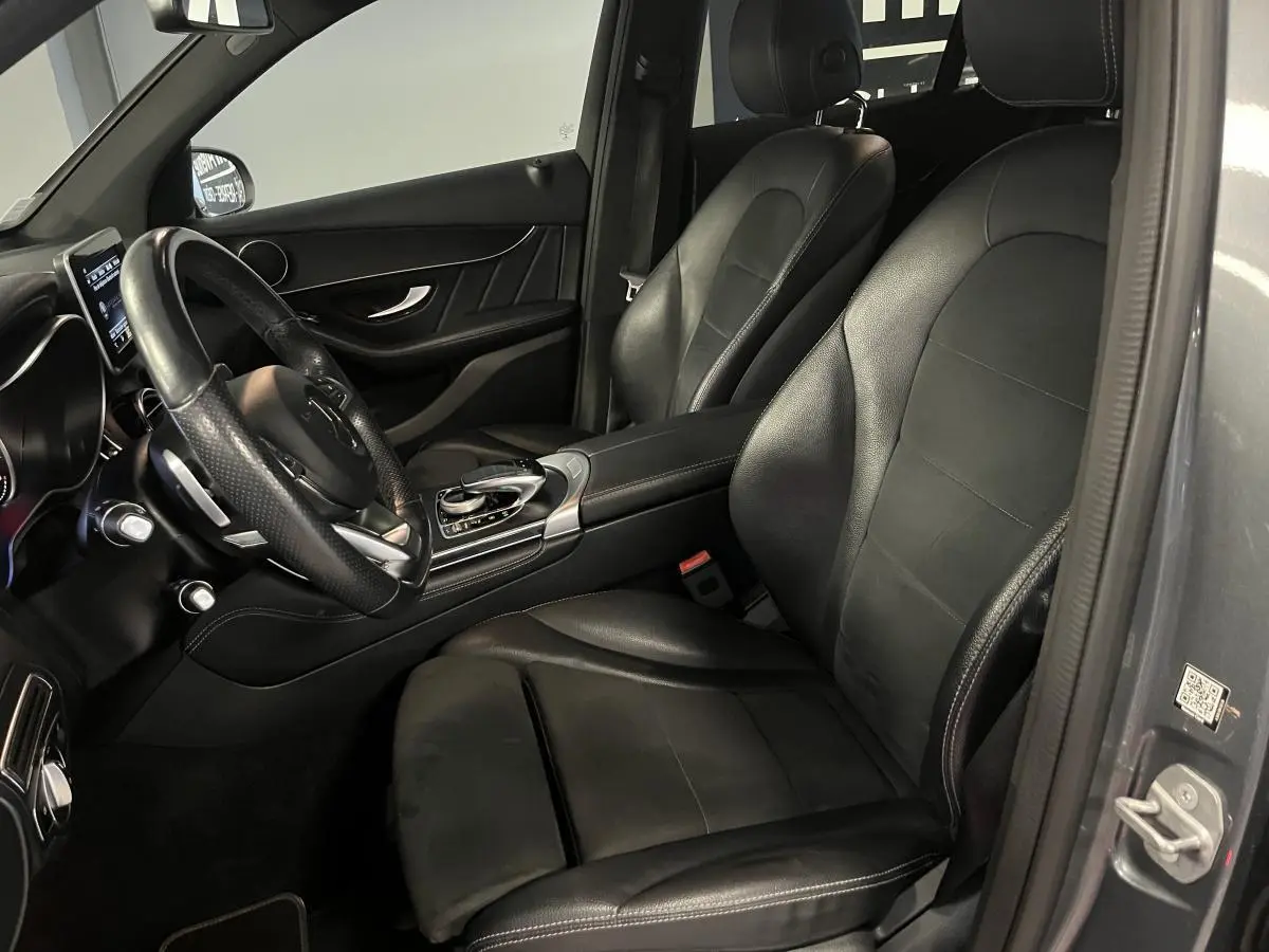 Vue intérieure côté conducteur du Mercedes GLC 220 d Sportline gris avec sièges cuir noir et volant multifonctions.