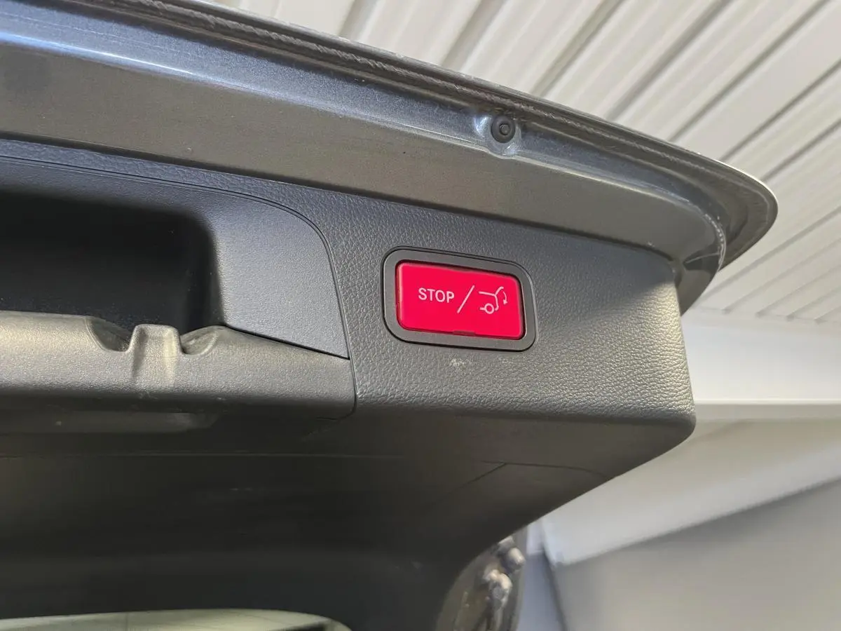 Bouton rouge d'arrêt d'ouverture du hayon sur le coffre gris d'un Mercedes GLC 220 d Sportline 2019.