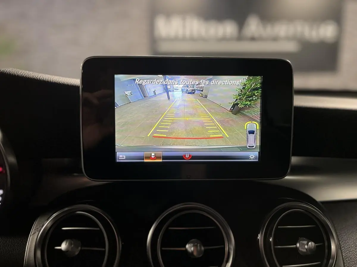 Écran central montrant la caméra de recul du Mercedes GLC 220 d Sportline gris, intérieur noir avec aérateurs ronds.