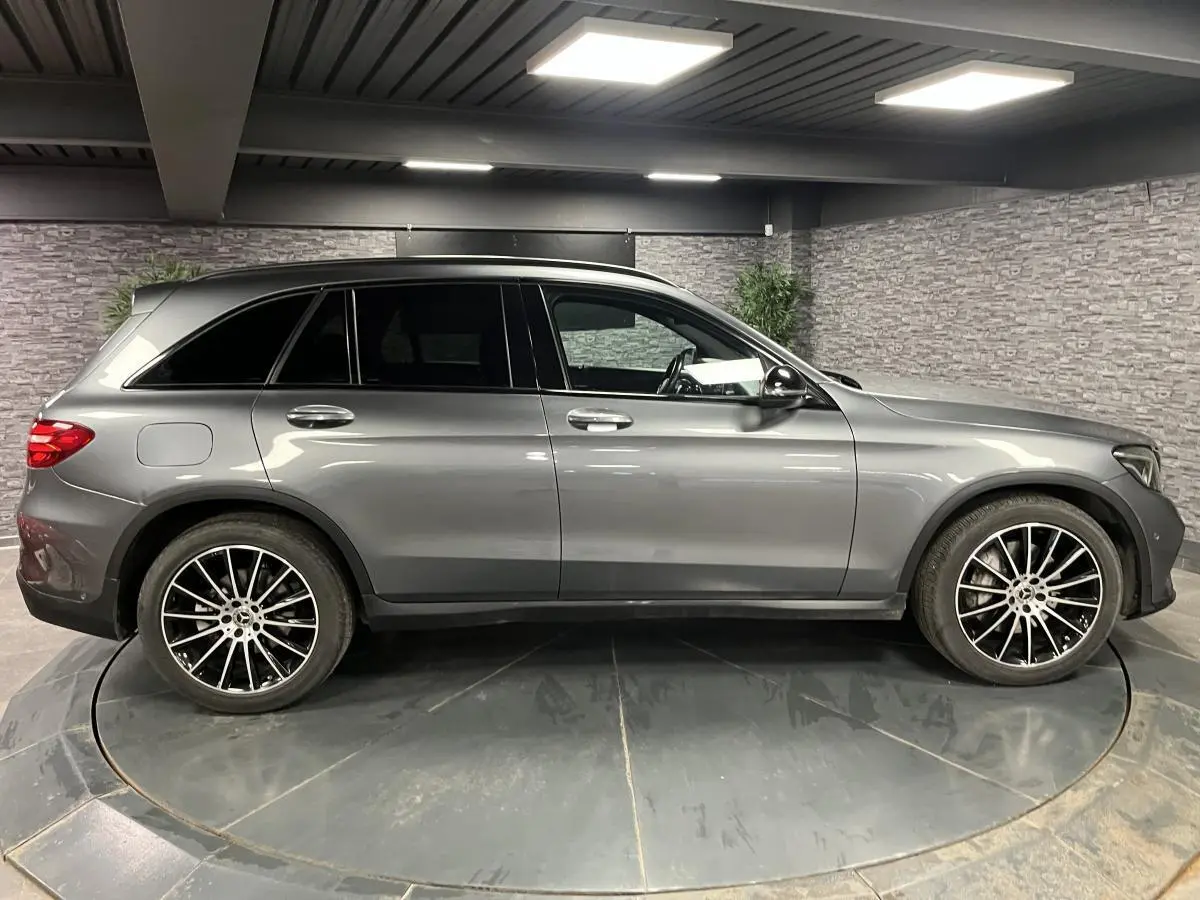 Profil droit d'un Mercedes GLC gris métallisé avec jantes AMG 20 pouces multibranches dans un garage.