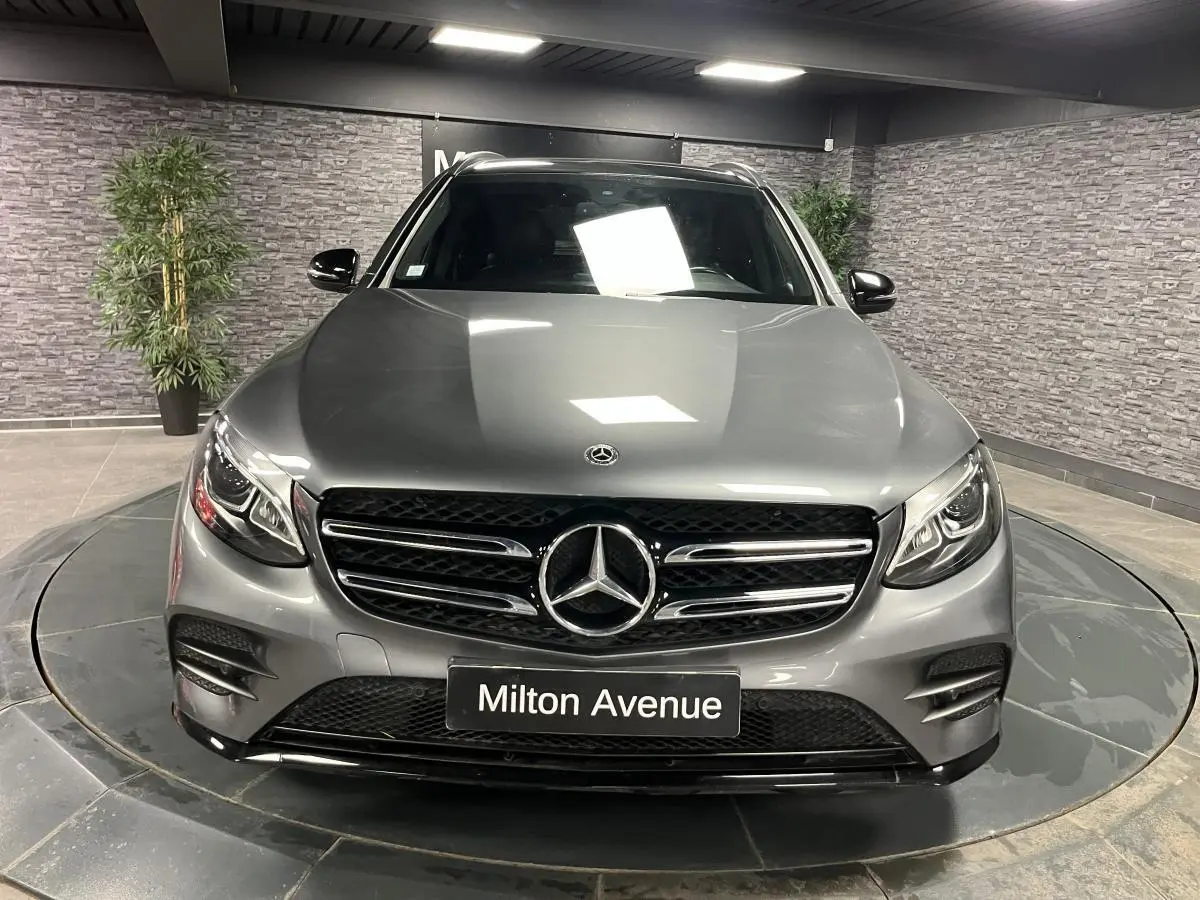 Mercedes GLC 220 d Sportline gris métallisé vu de face, avec calandre AMG et phares LED allumés.