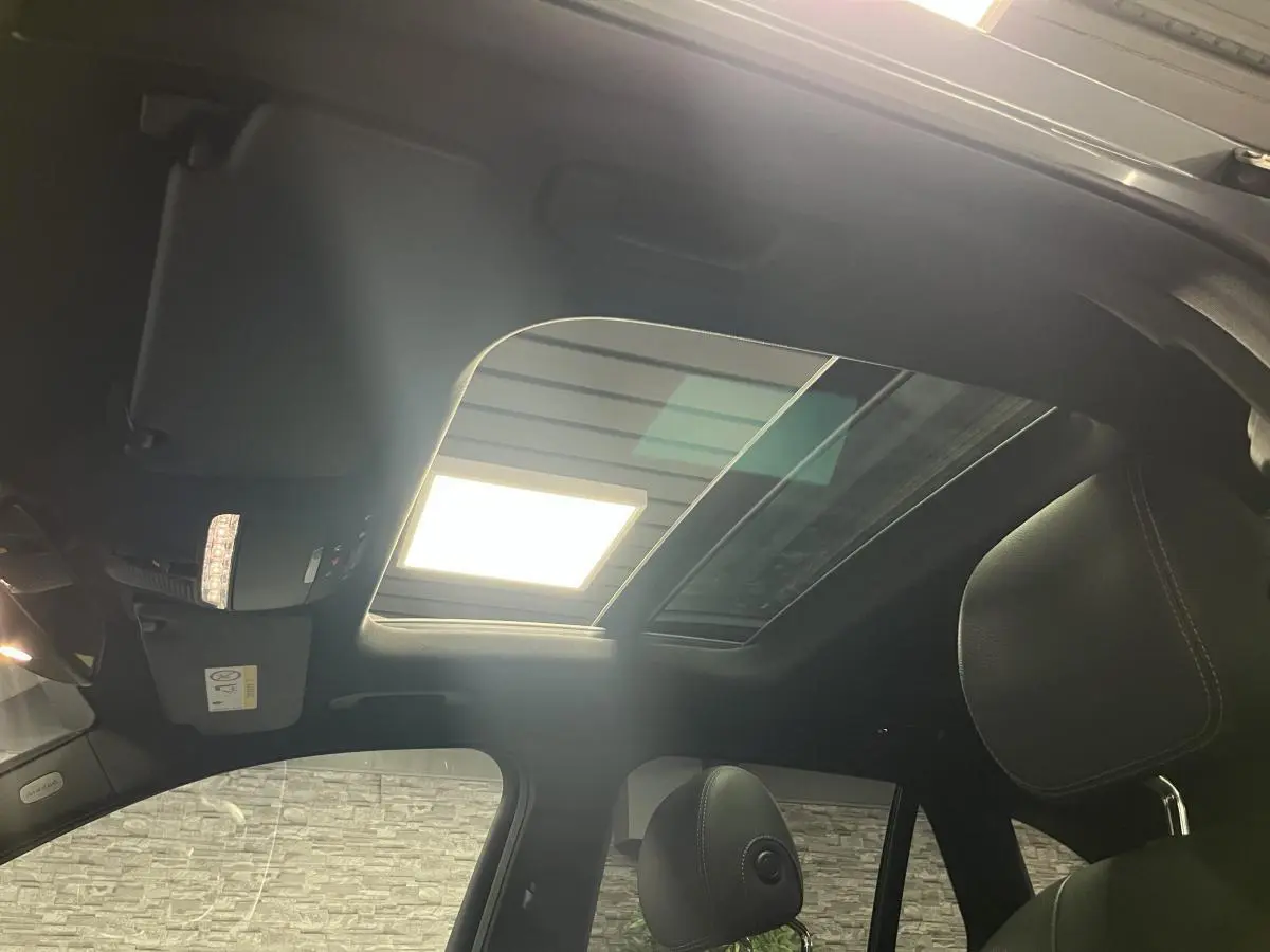 Toit ouvrant panoramique en verre vu de l'intérieur sur un Mercedes GLC gris, avec sièges en cuir noir.