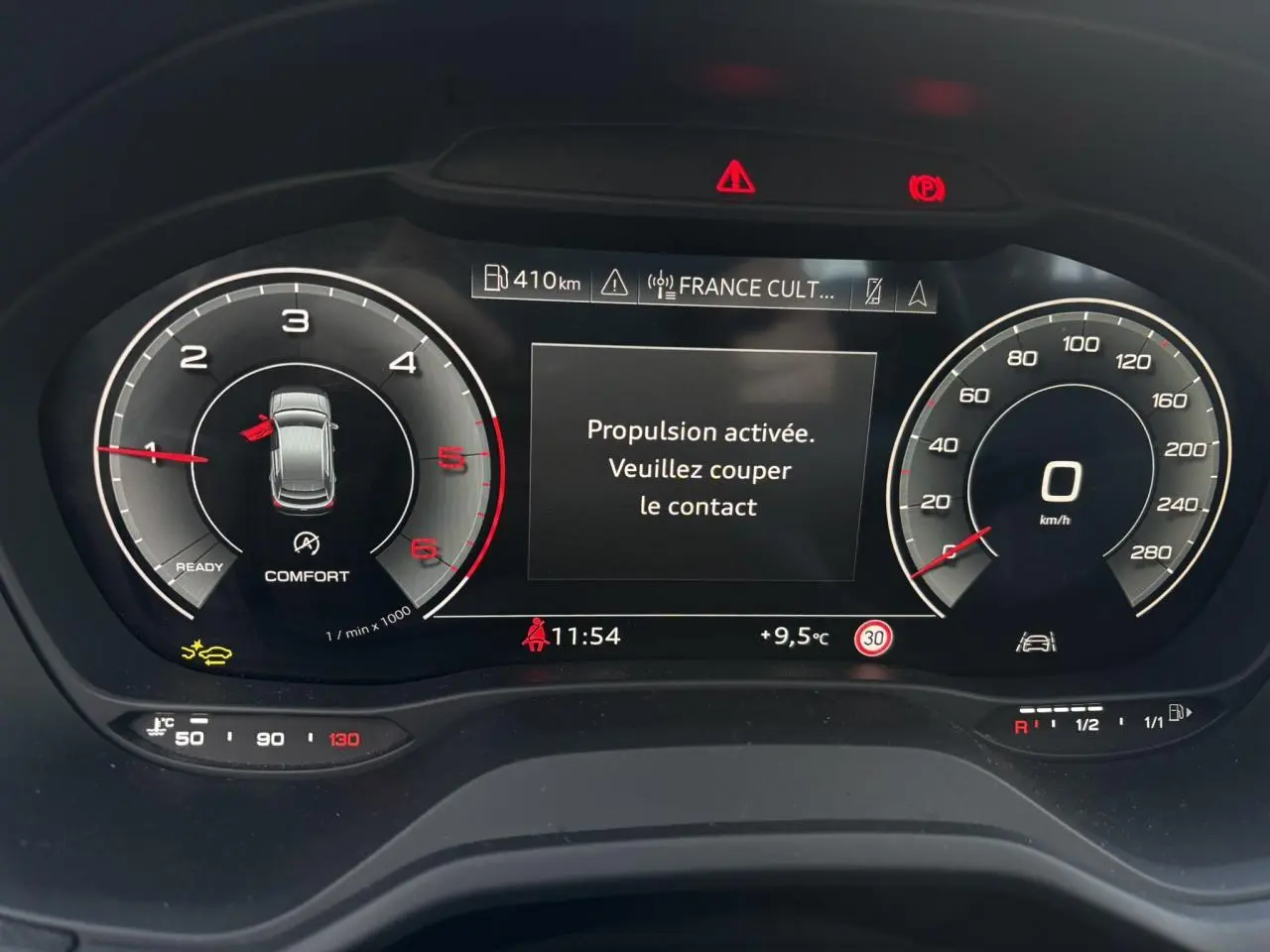 Vue rapprochée du tableau de bord numérique de l'Audi Q2 30 TDI S-Line 2025 affichant la vitesse, le régime moteur et un message d'alerte.