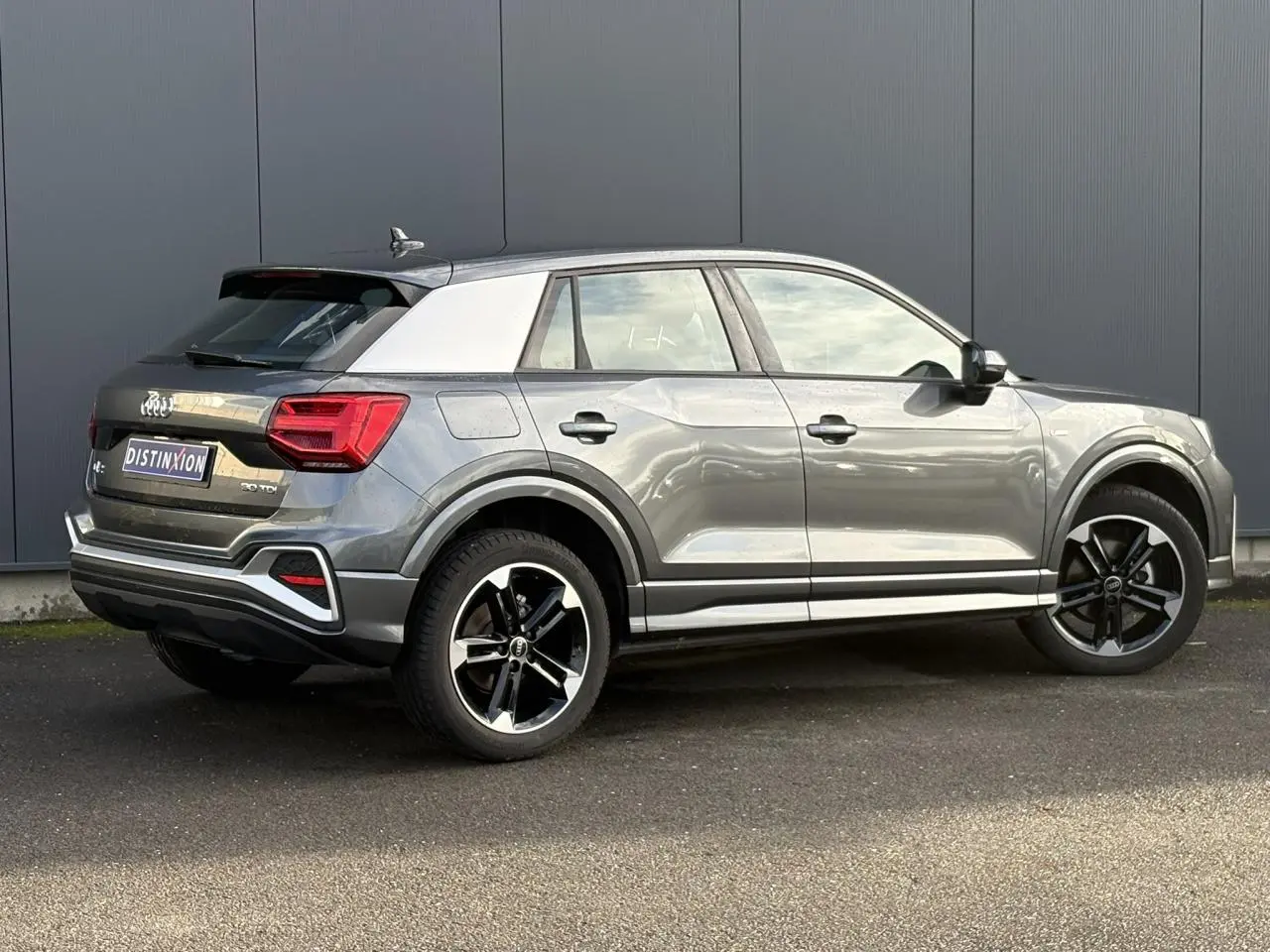 Audi Q2 30 TDI S-Line gris Daytona vue 3/4 arrière droit, avec toit contrasté blanc et jantes Audi Sport 5 branches.