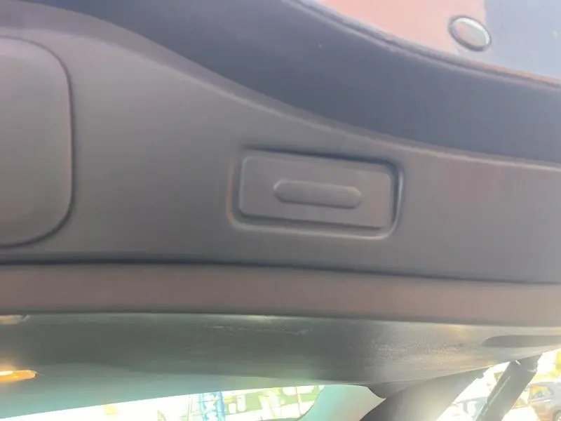 Détail du bouton d'ouverture électrique du hayon sur la partie intérieure du coffre du Renault Espace gris Cassiopée.