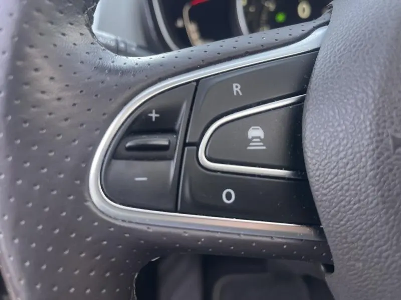 Gros plan sur les commandes noires du volant cuir perforé du Renault Espace Gris Cassiopée, version Initiale Paris.