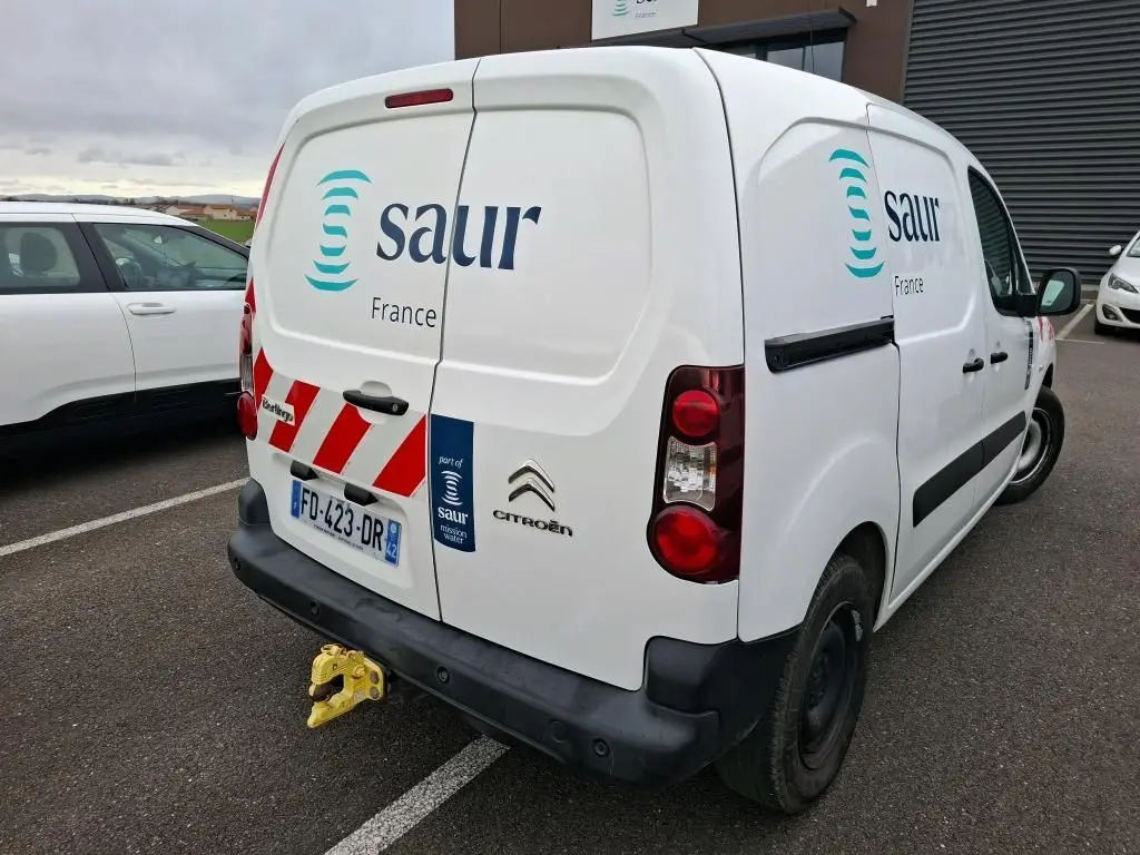 Vue 3/4 arrière droite d’un utilitaire Citroën Berlingo blanc avec logo Saur et marquages rouges sur porte arrière.