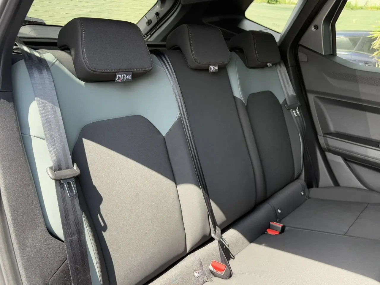 Vue latérale des sièges arrière bicolores gris et noir du Dacia Duster 2025 avec ceintures et appuie-têtes visibles.
