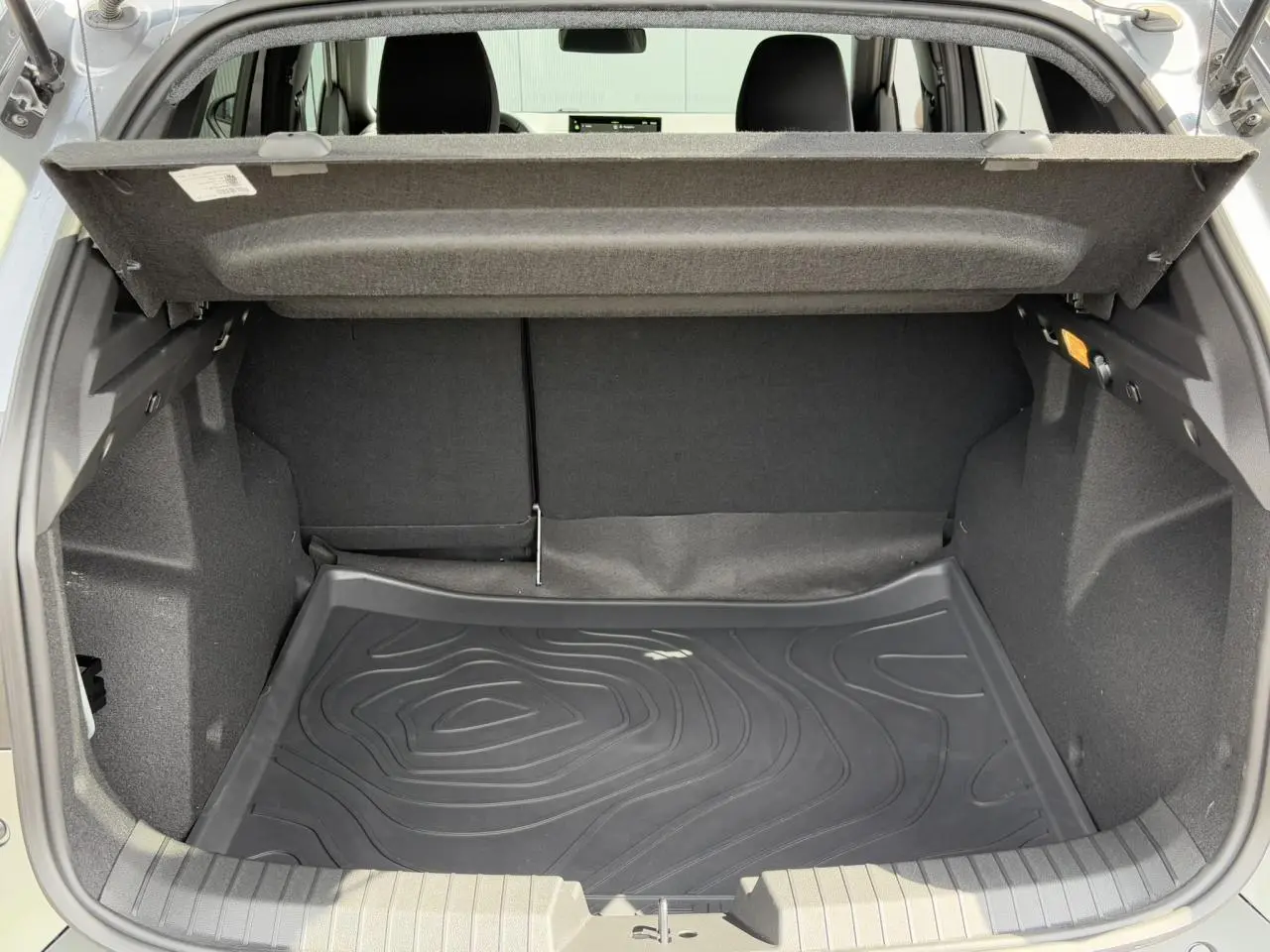 Coffre ouvert du Dacia Duster TCE 4x2 Mild Hybrid 130 gris Schiste, avec tapis de protection noir et intérieur spacieux.