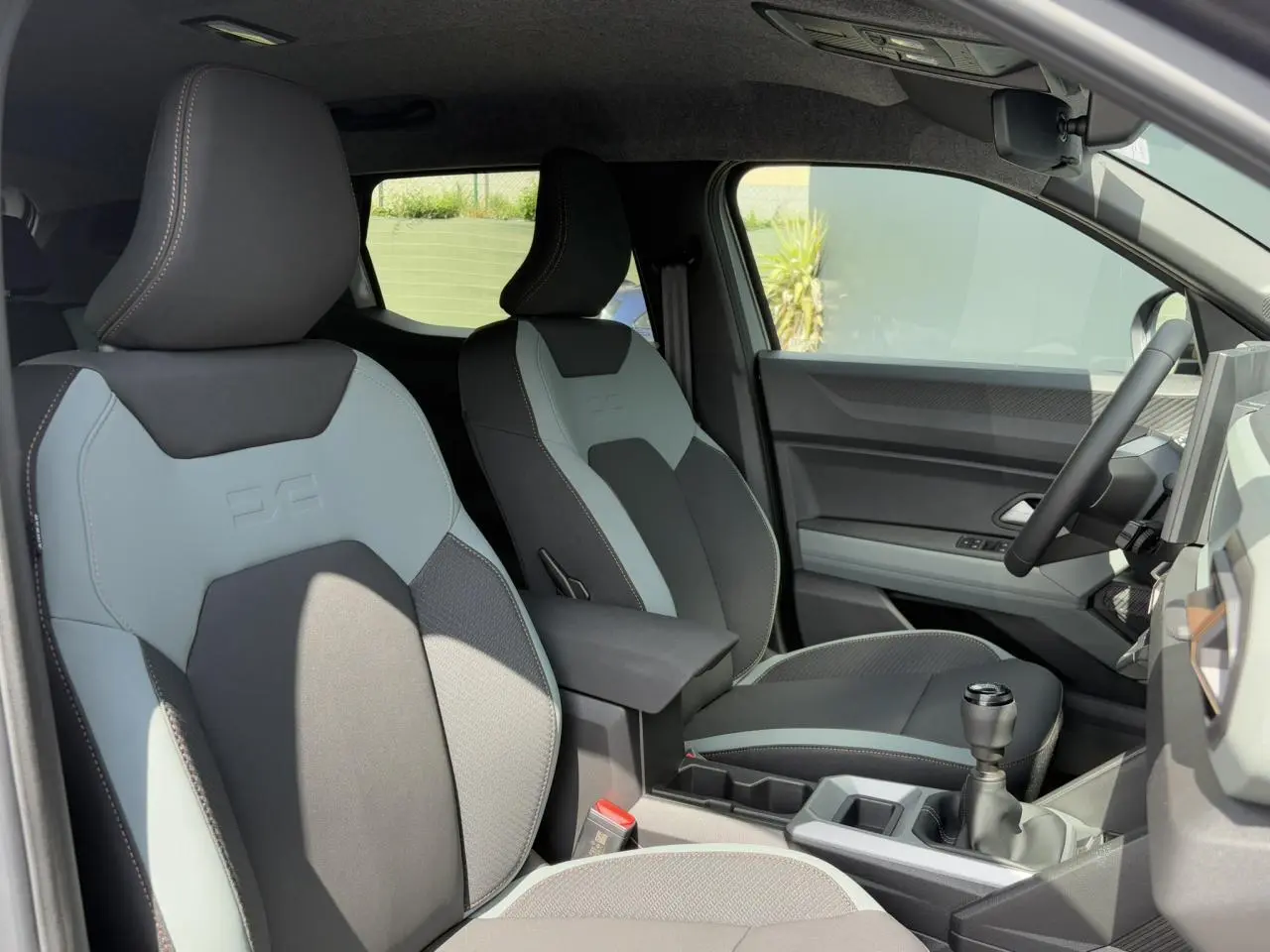 Vue intérieure côté conducteur du Dacia Duster 2025 avec sièges TEP bicolores gris et noir et volant soft feel.