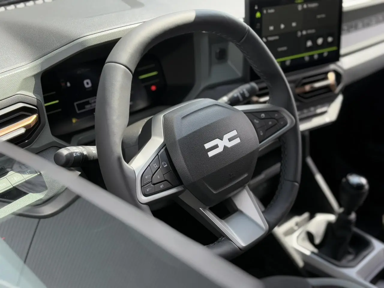 Vue rapprochée du volant et tableau de bord digital du Dacia Duster gris Schiste 2025 avec boîte manuelle.