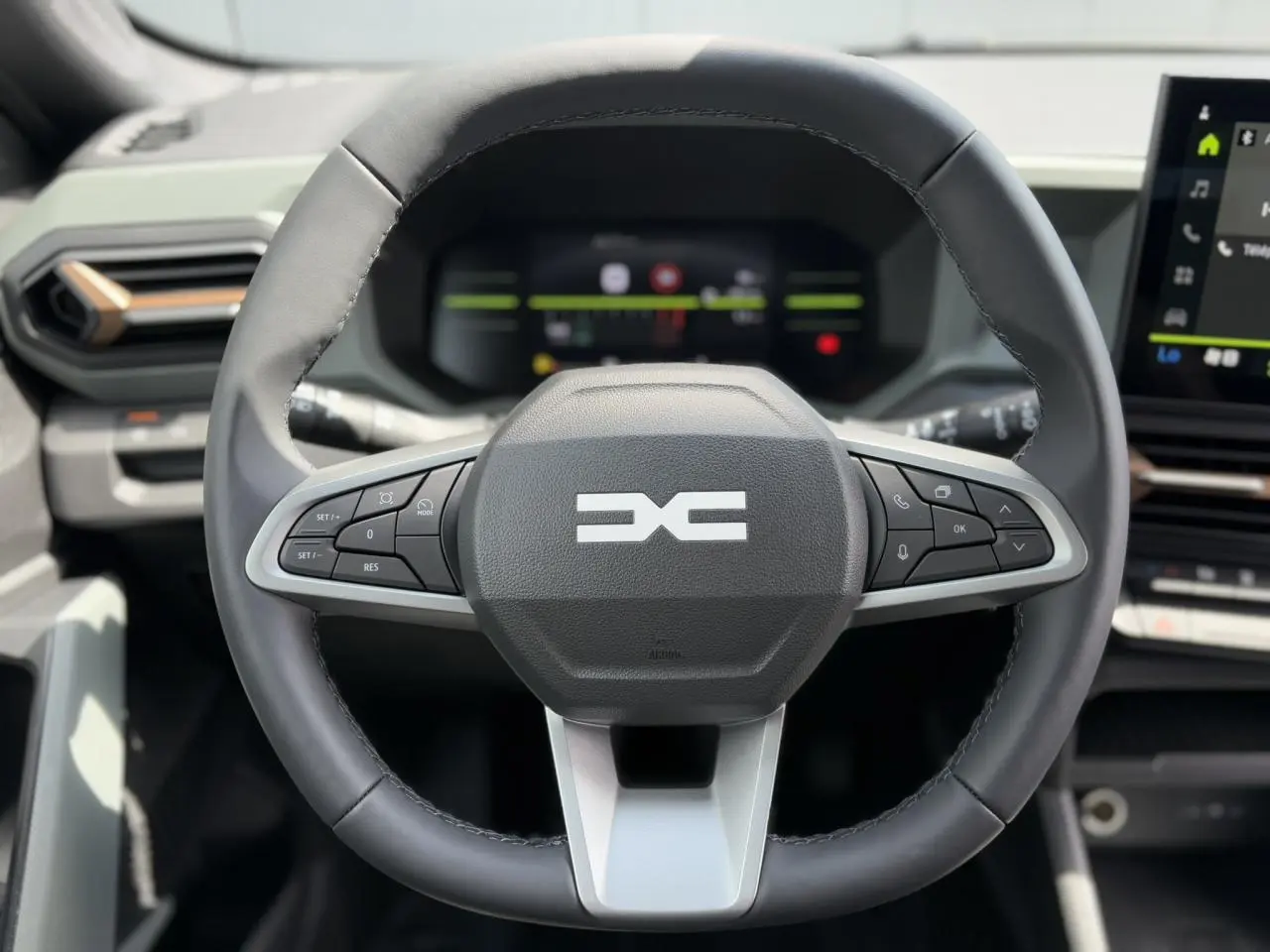 Volant multifonctions noir du Dacia Duster 2025 avec logo Extrême et tableau de bord digital en arrière-plan.