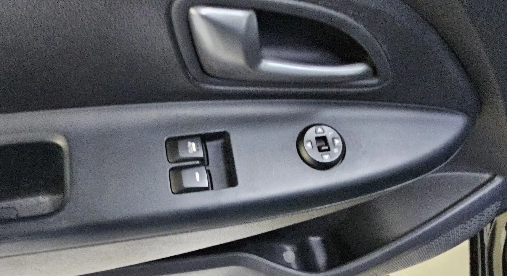 Poignée intérieure et commandes des vitres côté conducteur d'une Kia Rio III noire, version 3 portes de 2015.