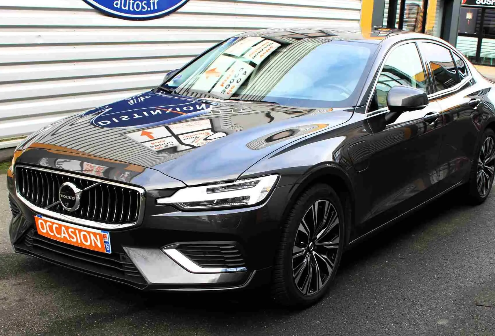 Volvo S60 gris métal vue 3/4 avant droit, calandre chromée et jantes alliage distinctives visibles.