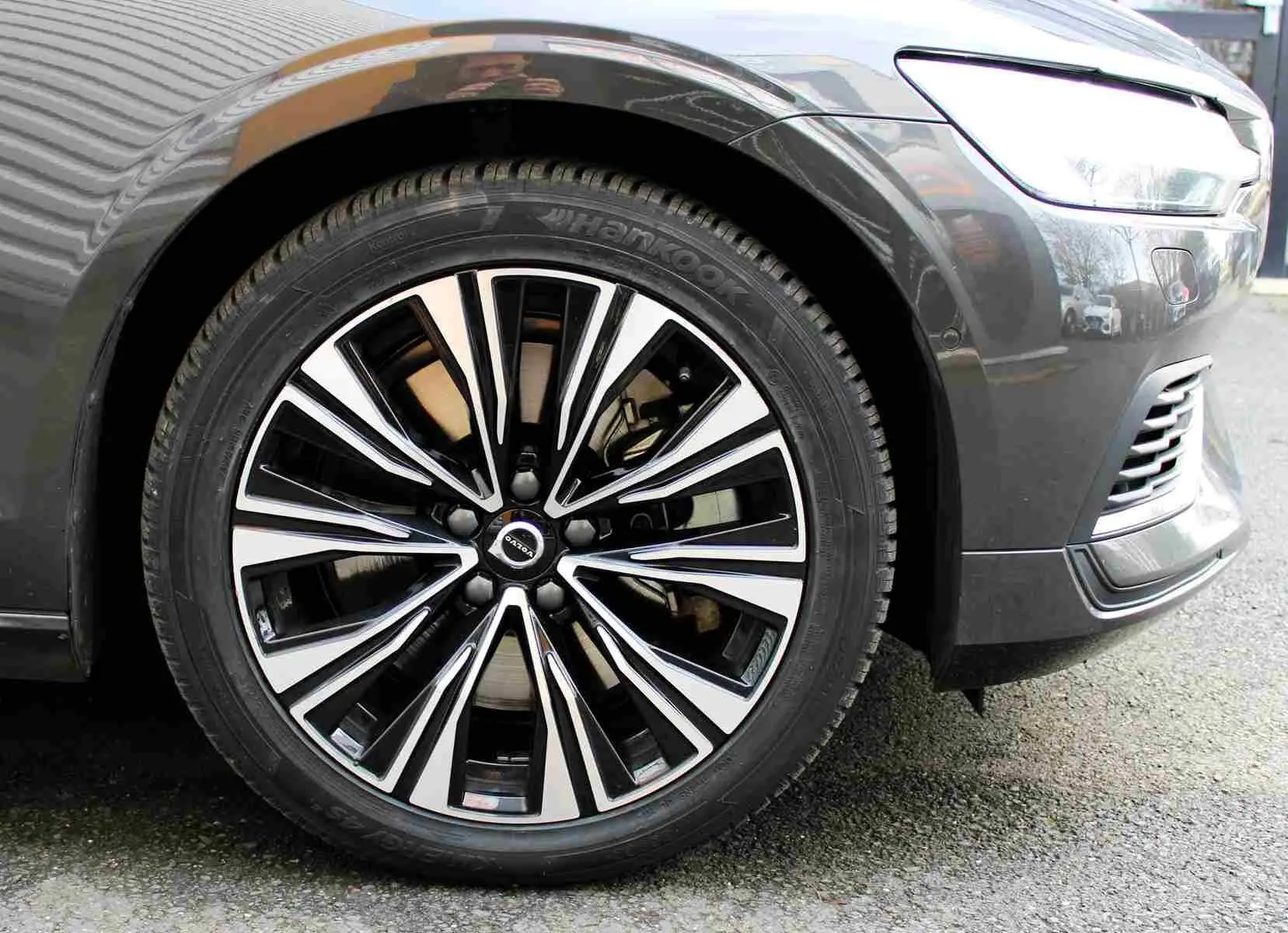 Gros plan sur la roue avant droite d'une Volvo S60 2024 gris métal, avec jante alliage noir et argentée distinctive.